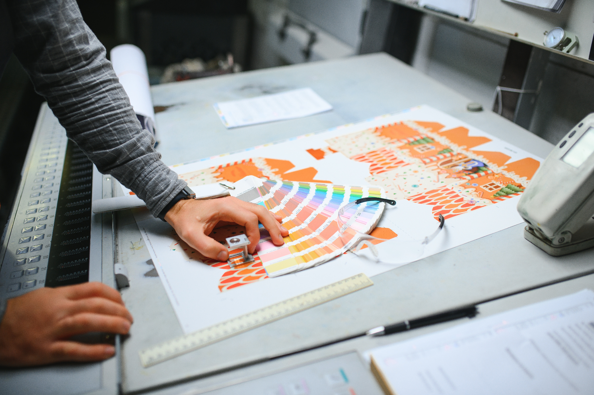 Press-check with Pantone swatch fan across a printed sheet